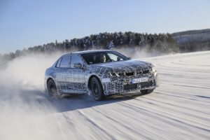 The BMW i3 being tested on frozen lake surfaces near Arjeplog, Sweden. The silver car is being driven fast, throwing up snow and ice